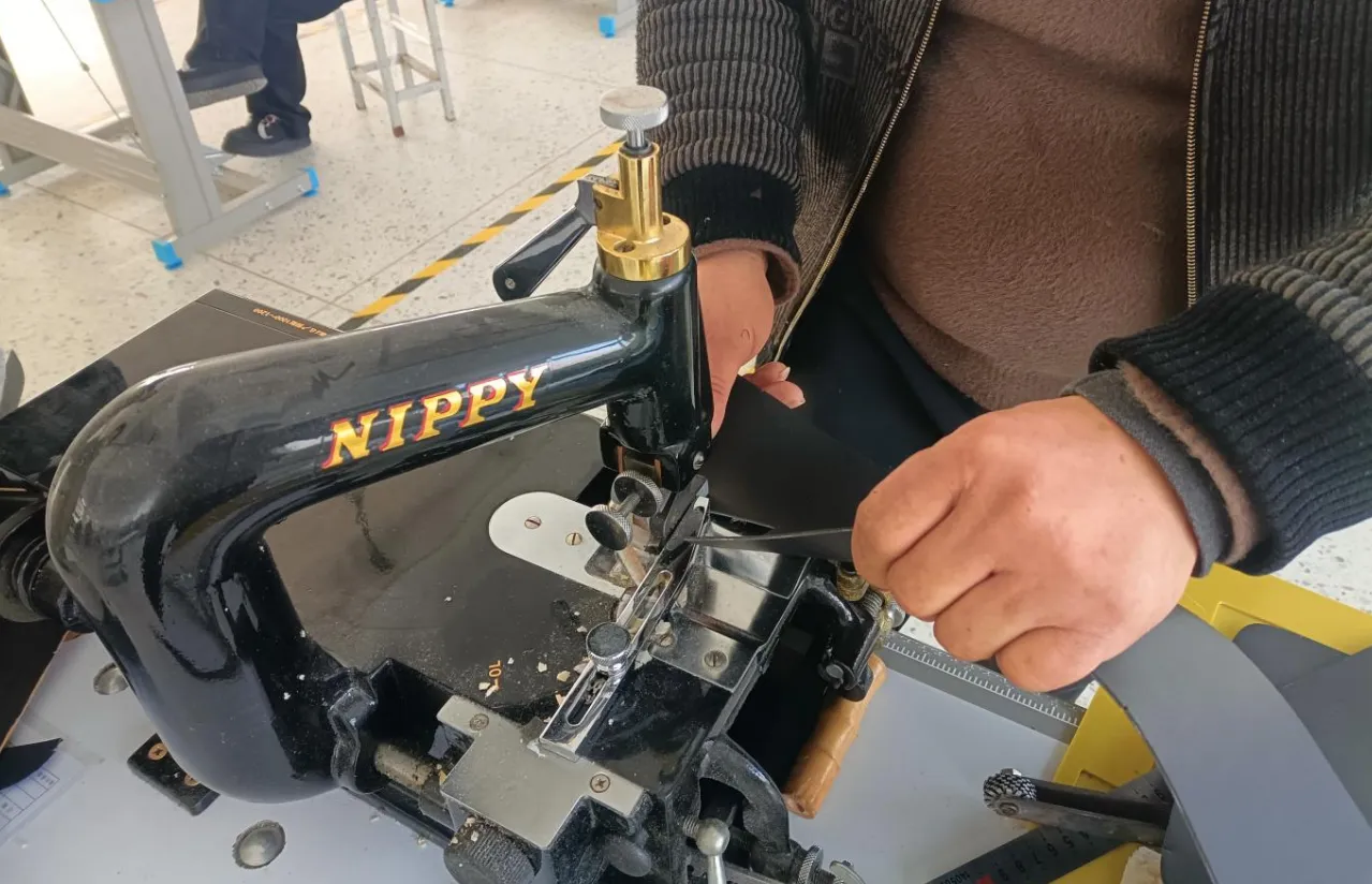 Operator running a leather panel through an edge skiving machine